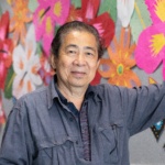 Photo of a man standing in front of a colorful flower mural.
