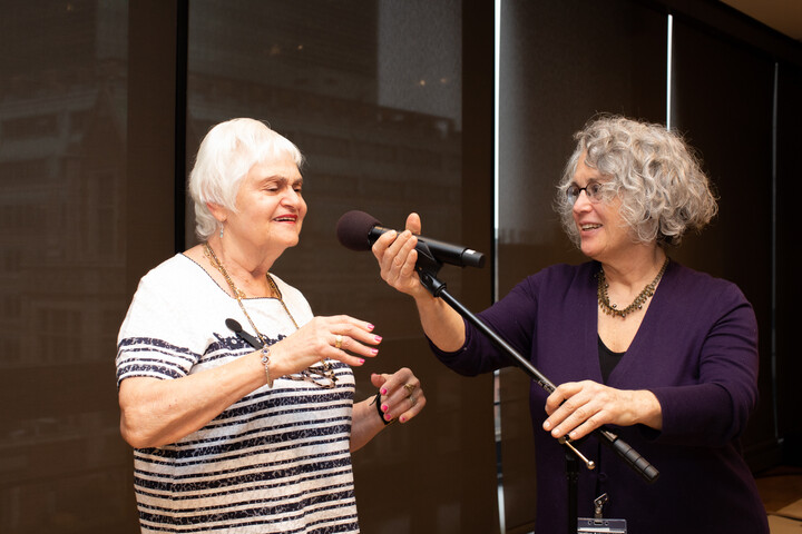 Two women stand at a microphone before a storytelling performance.