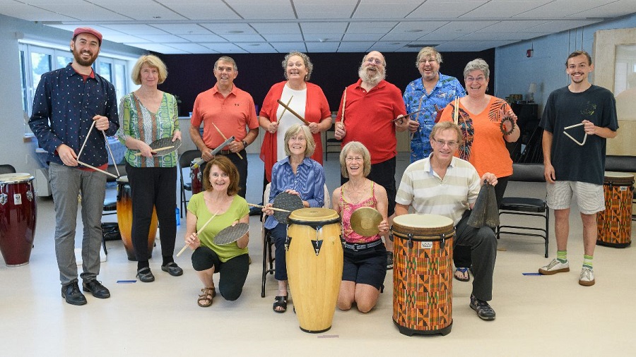 A group photo of participants posing and smiling at the camera with instruments in hand.