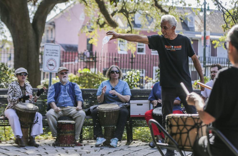Teaching artist, Luther Gray, pours libations for ancestors onto the cobblestones of Congo Square in Louisiana. Participants watch in the background.