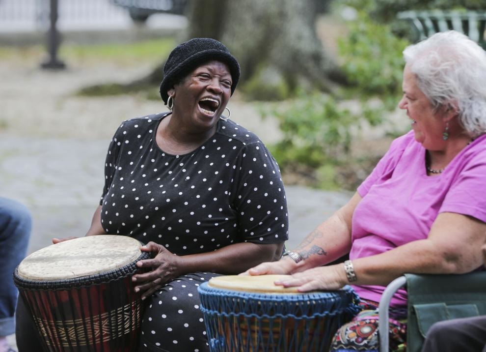 A participant laughs with another participant while playing drums.